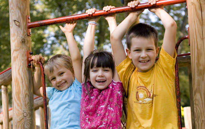 kids hanging from a metal bar at a playground