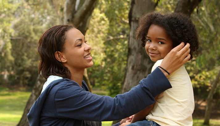 mom talking with young girl while straightening her hair